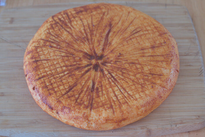 A round of cheese on a wooden board, the rind dusted in a star pattern
