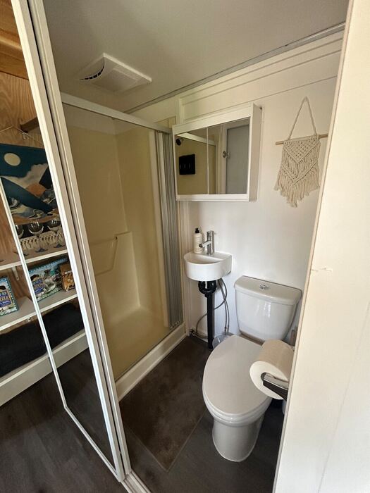 The bathroom &mdash; a corner shower, wall-hung sink, and just enough room, fitted efficiently into a tiny footprint