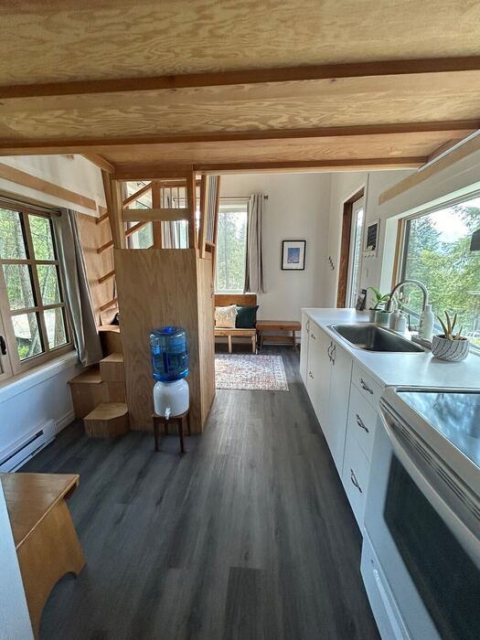 Inside the tiny house &mdash; stairs to the loft, the kitchen run, and the living nook under a wood ceiling