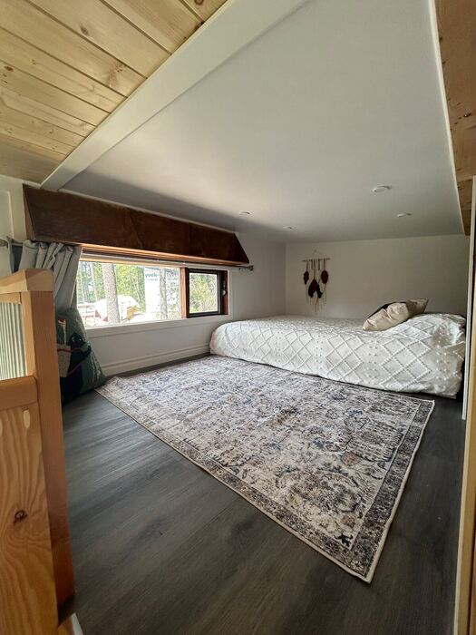 The sleeping loft &mdash; a wide bed under a low ceiling