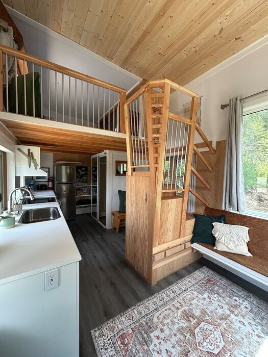 Wooden stairs leading up to the sleeping loft, with slat railings and the loft floor visible above